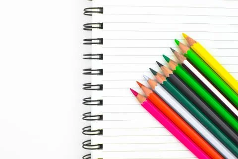 Various colored pencil crayons placed in a waved form row before a diary Stock Photos