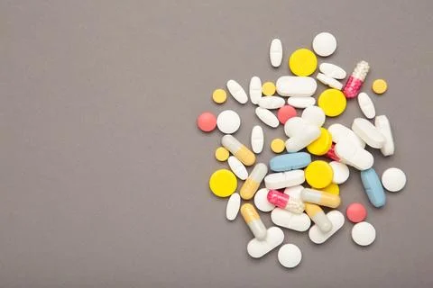 Various colored pills on grey background. Space for text Stock Photos