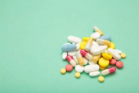 Various colored pills on mint background. Space for text Stock Photos