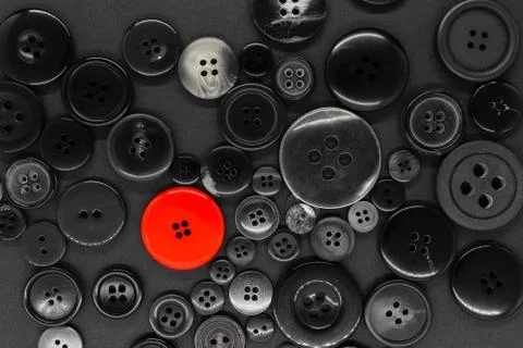Various dark clothes buttons background with one red button Stock Photos