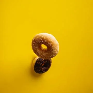 Various decorated doughnuts in motion falling on yelloy background Foto stock