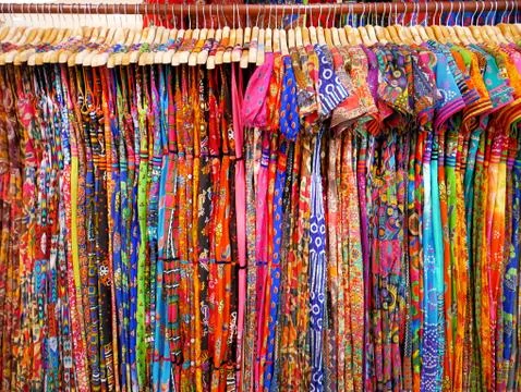 Various Designs of Colorful Women's Patterned Clothes Hanging on Rack Foto stock