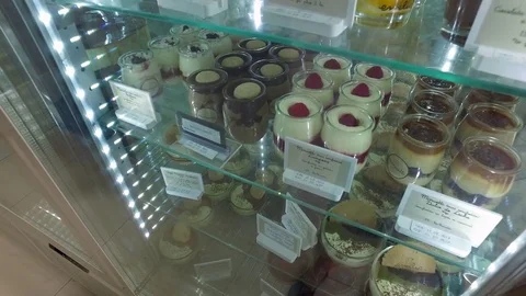 Various desserts in a display case at a bakery and ice cream parlor Stock Footage 80380623