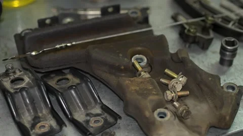 Various disassembled car engine parts, including brackets, metal plates, bolt Stock Footage 345109059
