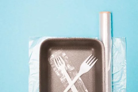 Various disposable plastic packaging on a blue background, a food tray, a rol Stock Photos