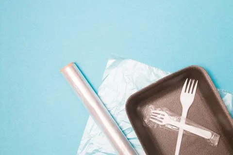 Various disposable plastic packaging on a blue background, a food tray, a rol Stock Photos