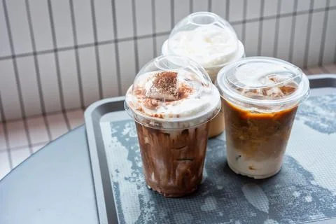 Various drinks in plastic cups on the table in the mall. Selective focus Stock Photos