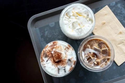 Various drinks in plastic cups on the table in the mall. Selective focus Stock Photos
