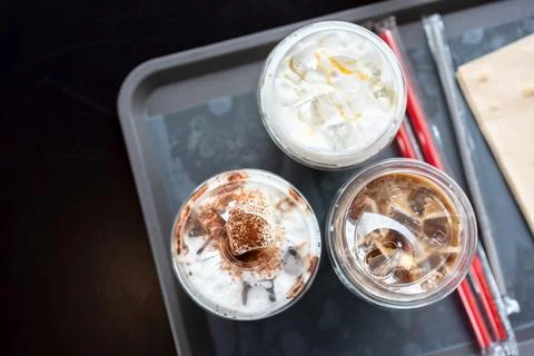 Various drinks in plastic cups on the table in the mall. Selective focus Stock Photos