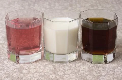 Various drinks in three glasses on the background of a linen tablecloth Stock Photos
