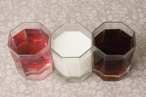 Various drinks in three glasses on the background of a linen tablecloth Stock Photos
