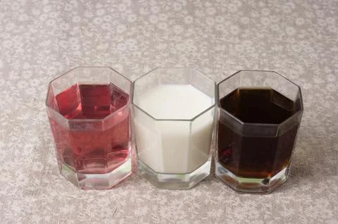 Various drinks in three glasses on the background of a linen tablecloth Stock Photos