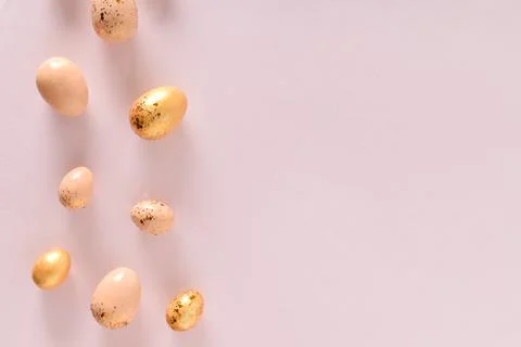 Various Easter eggs of yellow shades lie on a pink background. Copy space. Fl Stock Photos
