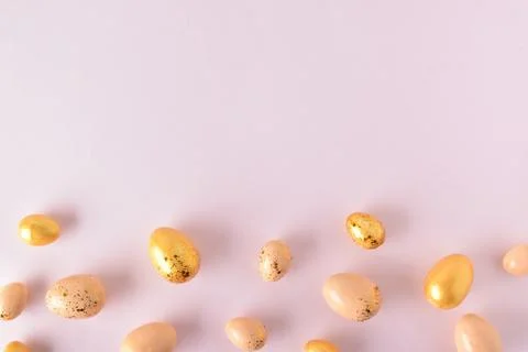 Various Easter eggs of yellow shades lie on a pink background. Easter backgro Stock Photos