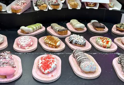 Various eclairs and donuts, each uniquely decorated with colorful glazes, top Stock Photos