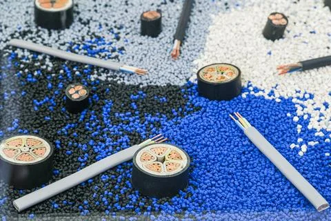 Various electric cable and wire samples displayed on plastic granules. Stock-Fotos