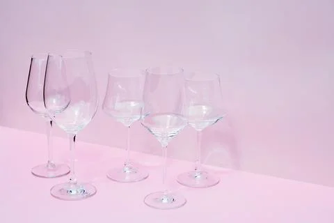 Various empty wine glasses on a pink background with space for text. Stock Photos
