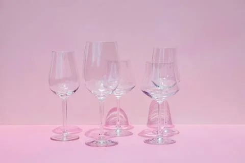 Various empty wine glasses on a pink background with space for text. Stock Photos