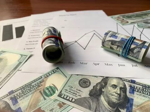 Various financial analysis documents are spread on a wooden table, alongside Stock Photos