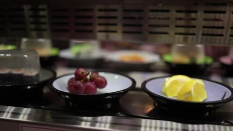 Various food items are moving on the rotating conveyor, including sushi and frui Stock Footage 303286554