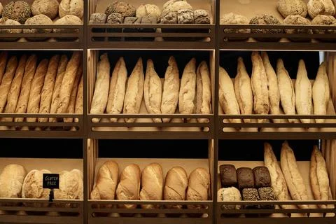 Various fresh breads on shelf in artisan bakery with rustic setup Stock Photos
