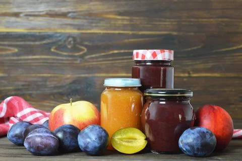 Various fruit jam jars and fresh fruits Stock Photos