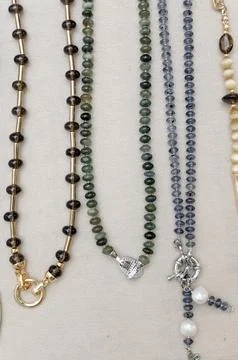 Various gemstone necklaces displayed on a neutral fabric background Stock Photos