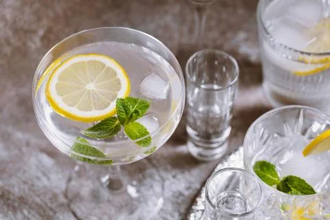 Various glasses on silver tray filled with cold drinks with ice, lemon, mint Stock Photos
