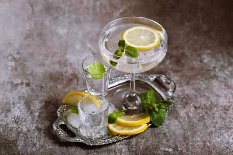 Various glasses on silver tray filled with cold drinks with ice, lemon, mint Stock Photos