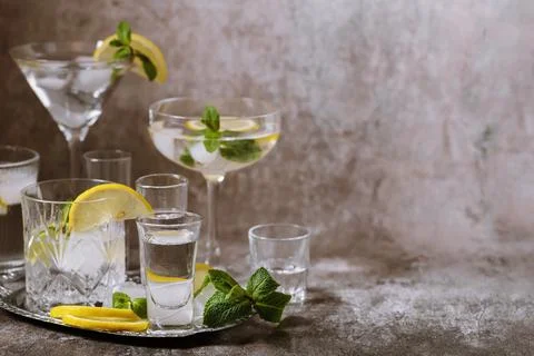 Various glasses on silver tray filled with cold drinks with ice, lemon, mint Stock Photos