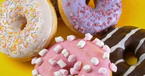 Various glazed sweet donuts rotating with yellow background Stockbeeldmateriaal 122178239