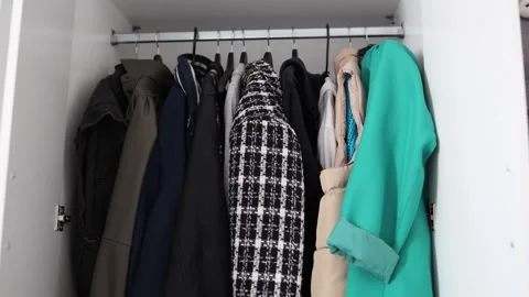 Various jackets and coats hang neatly on a clothing rack inside a modern white w Stock Footage 312198211