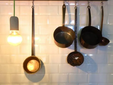 Various kitchen utensils hanging on the wall of a restaurant Stock Photos