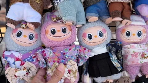 Various Labubu plush dolls dressed in miniature designer-inspired outfits Stock Footage 329011535