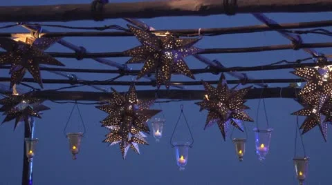 Various lanterns and lights hanging from a trellis at sunset Video stock 11681622