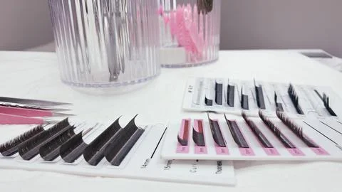 Various lash extensions, palettes, and beauty tools in soft white and pink to Stock Photos