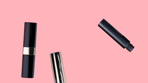 Various makeup accessories are falling down on a trendy pastel pink background Stock Footage 236811515