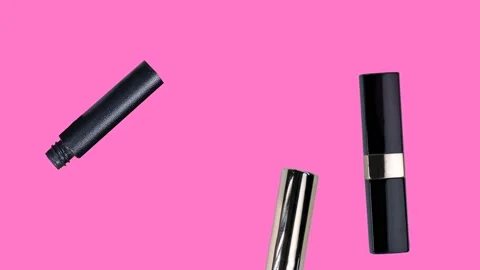 Various makeup accessories are falling down on a trendy pastel pink background Stock Footage 238536693
