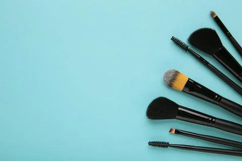 Various makeup brushes on blue background with copy space. Stock Photos