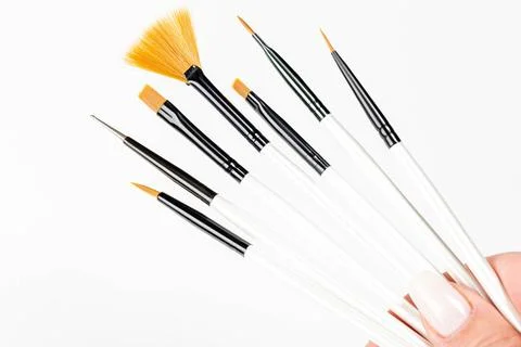 Various makeup brushes in a woman's hand on a white background Stock Photos