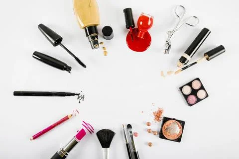 Various makeup products forming circular frame white background Stock Photos