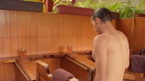 Various men at a spa getting inside steam boxes with the help of an employee Video stock 119801434