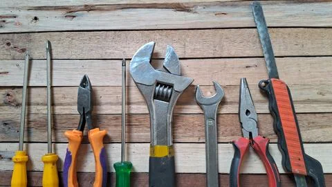 Various metal hand tools arranged neatly on a rustic wooden board Stock Photos
