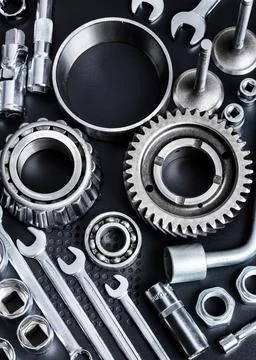 Various metallic tools and mechanical parts arranged on a dark surface Stock Photos