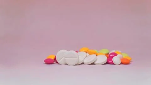 Various multicolor pills lying on light purple background Foto stock