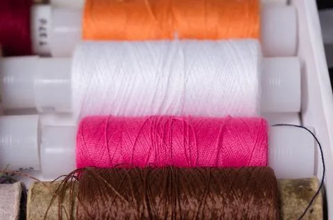Various multicolored used sewing threads in a box, stacked in a row Stock Photos