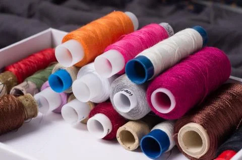 Various multicolored used sewing threads in a box, stacked in a pile Stock Photos