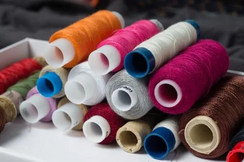Various multicolored used sewing threads in a box, stacked in a pile Stock Photos