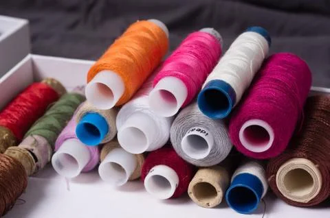 Various multicolored used sewing threads in a box, stacked in a pile Stock Photos