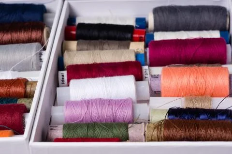 Various multicolored used sewing threads in a box, stacked in a pile Stock Photos